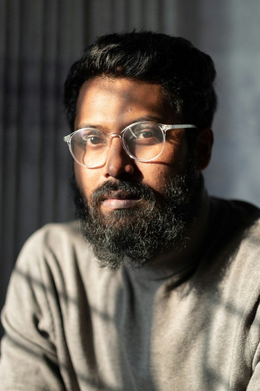Studio portrait of a bearded man with glasses in business casual attire