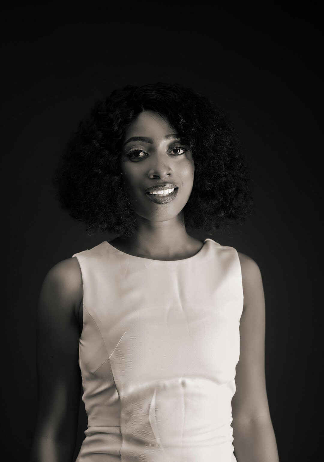 Studio portrait of a smiling woman with curly hair in professional attire