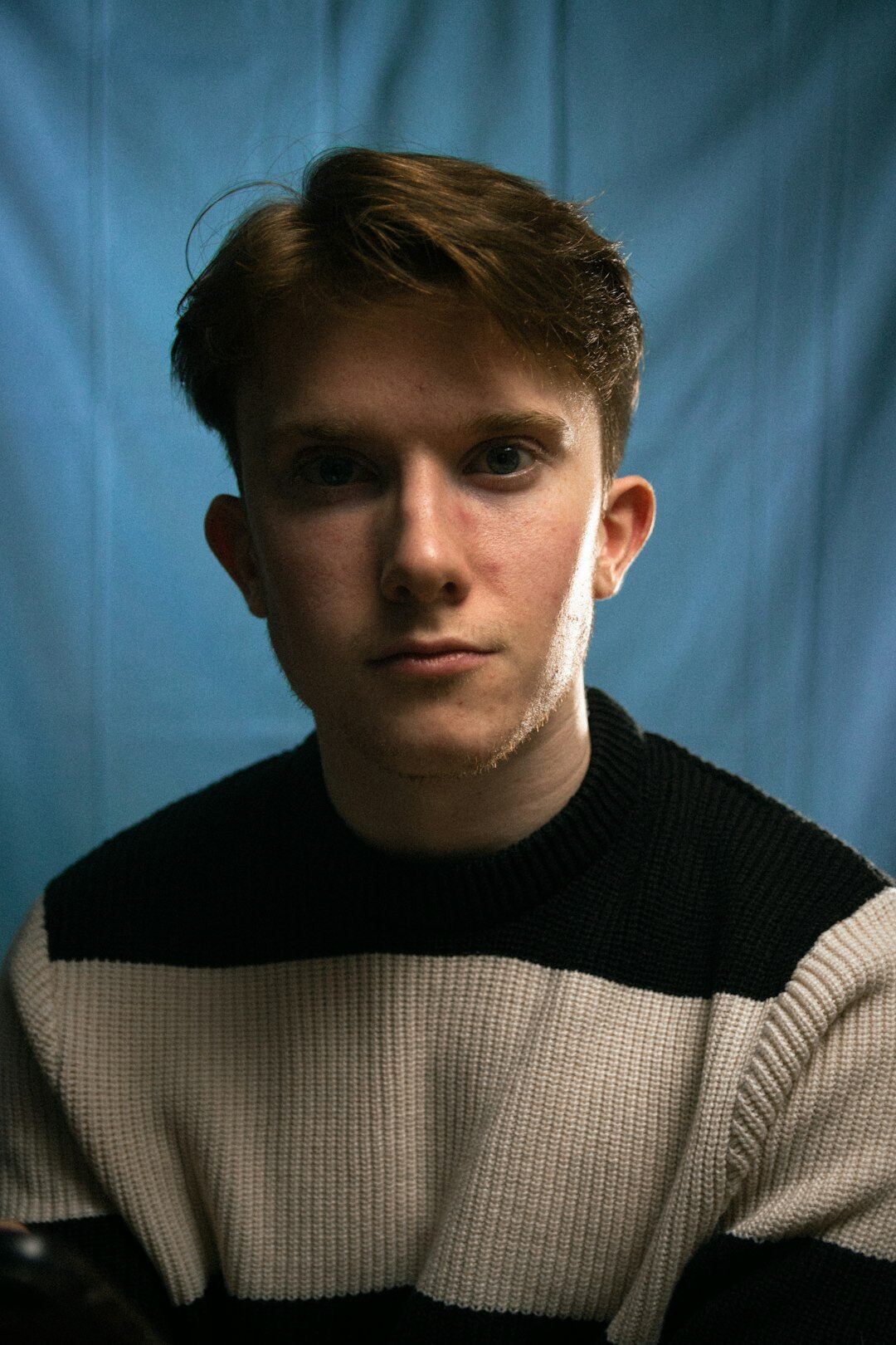 Studio portrait of a young man with short hair wearing a sweater